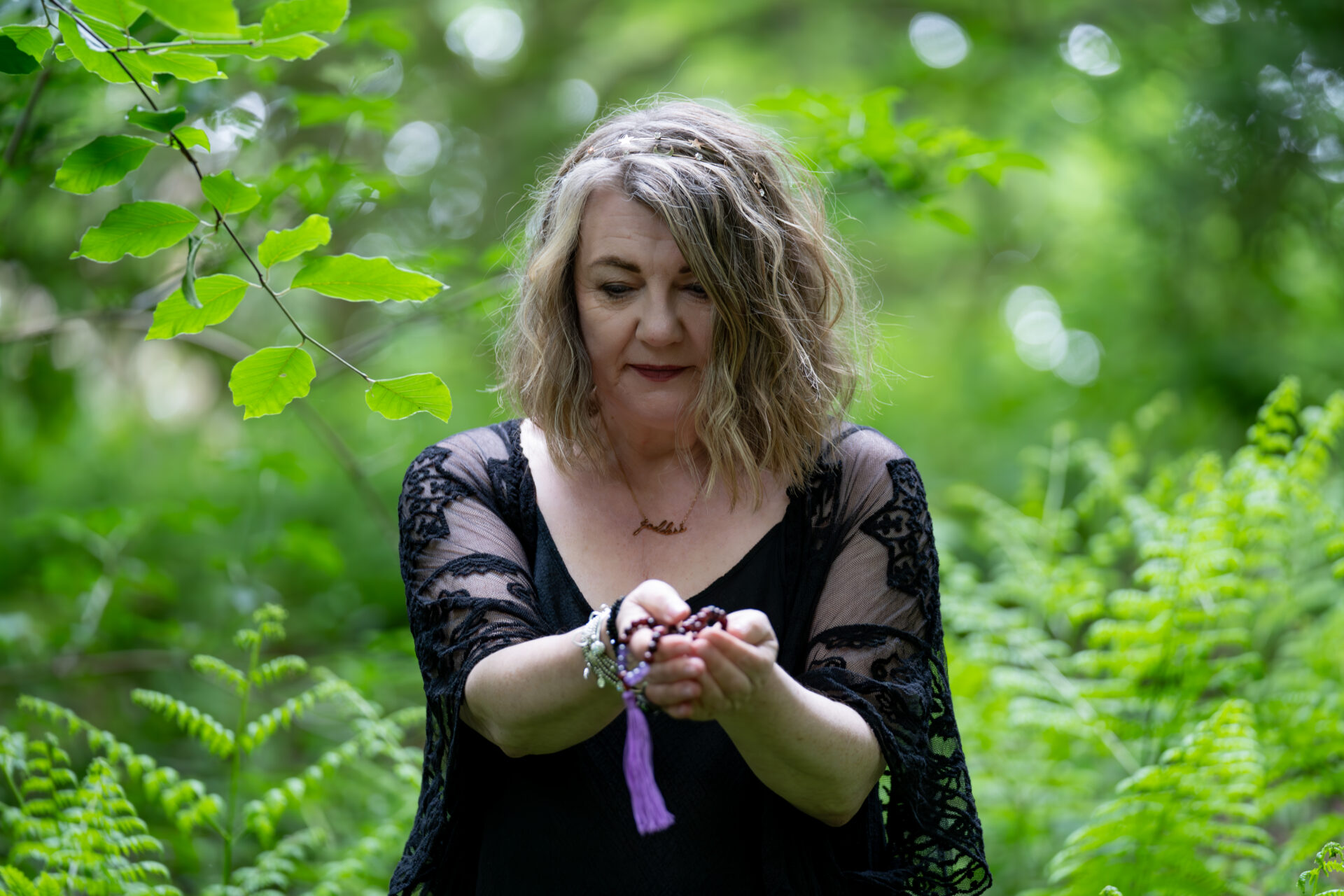 Ann holding an oracle card in woodland during a personal branding photoshoot